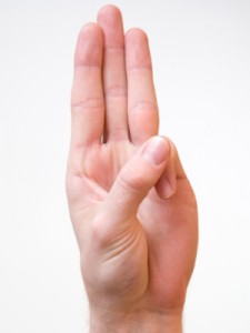Image of a hand doing the boy scout signal, with thumb over little finger and three middle fingers raised